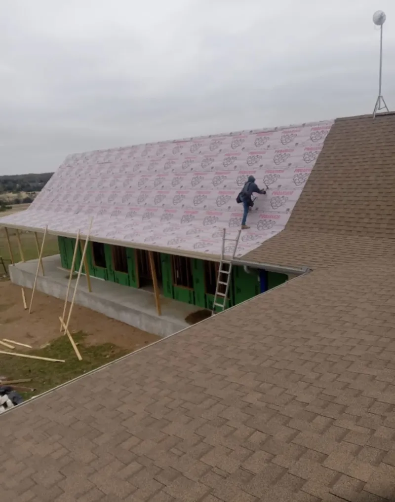 Worker preparing underlayment for a metal roof installation in Florissant
